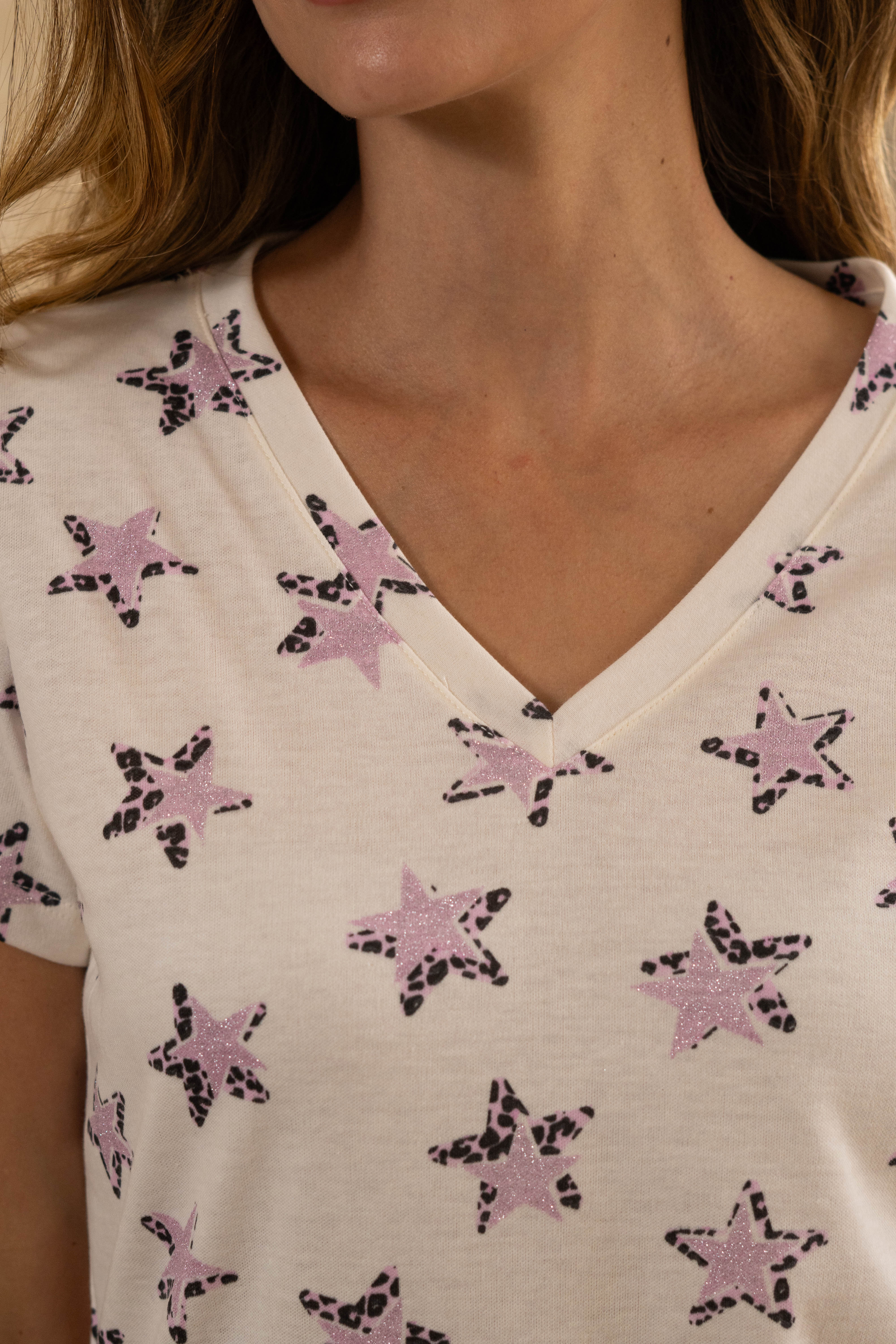 Pijama con diseño de pequeñas estrellas lila y negro sobre fondo claro, tela de polialgodón suave.